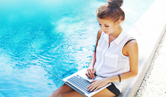 woman looking at laptop by pool