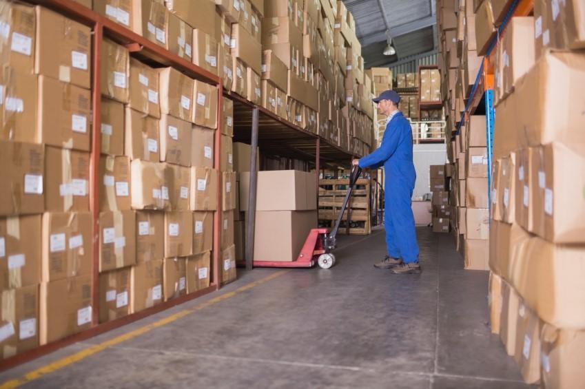 Warehouse worker moving boxing and keeping track of stock from stock control software